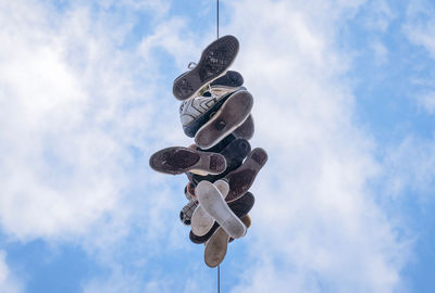 Low angle view of shoes hanging on pole against sky