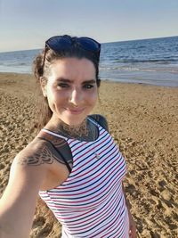 Portrait of smiling young woman standing on beach