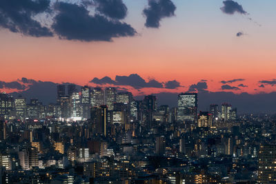 Illuminated buildings in city against sky during sunset