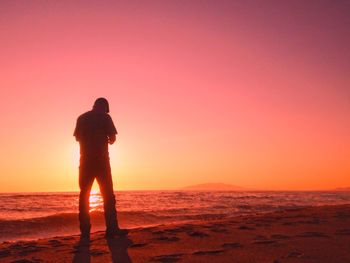 Silhouette man standing on beach during sunset