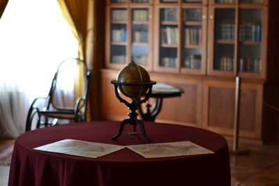 Globe on table against shelf in library