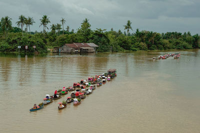 High angle view of people sitting in boats on lake against sky