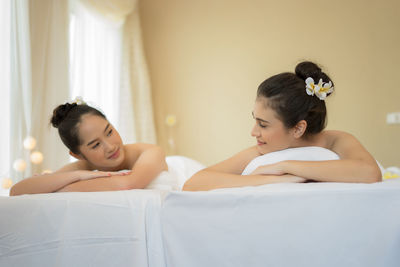 Young female friends lying on massage tables in spa