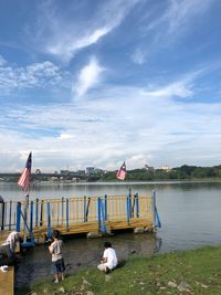 People on boat in lake against sky