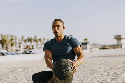 Mature man exercising with medicine ball on beach