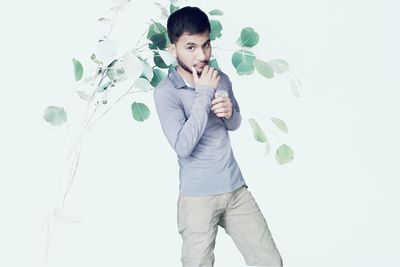 Portrait of young man standing against white background