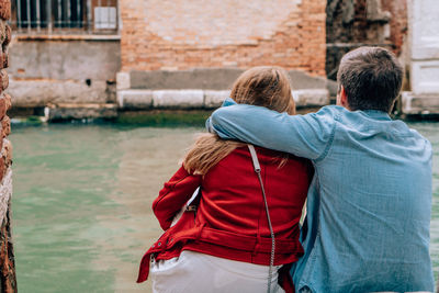 Rear view of couple kissing against canal