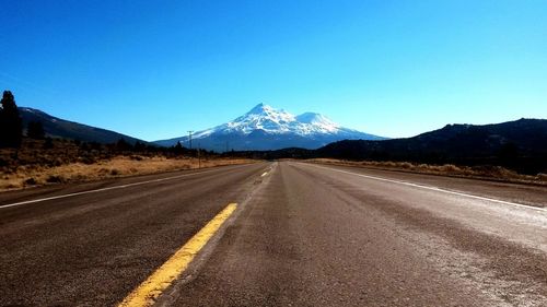 View of highway leading towards snowcapped mountain