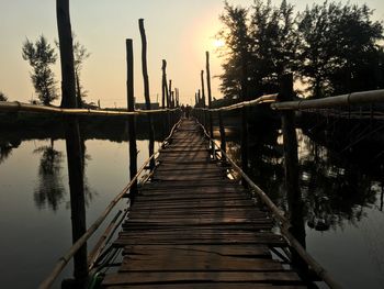 Wooden footbridge over lake against sky