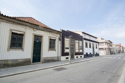 Road by buildings against sky in city