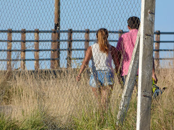 Low angle view of woman standing by fence