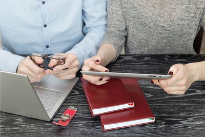 Midsection of woman using mobile phone on table