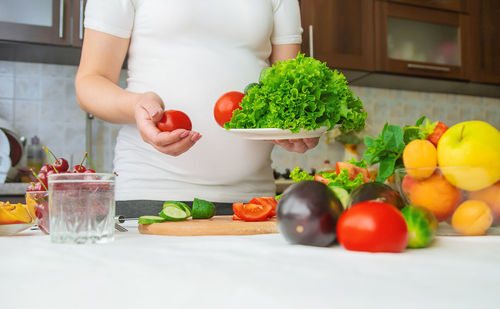 Midsection of pregnant woman with vegetables
