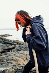 Side view of young woman standing at beach