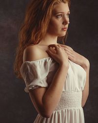 Portrait of young woman standing against gray background