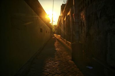 Alley amidst buildings in city at sunset