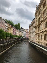 Canal amidst buildings in city against sky