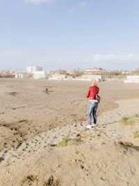 Rear view of man walking at beach against sky