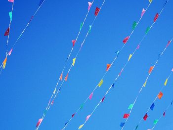 Low angle view of flags against clear blue sky