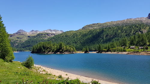 Scenic view of lake and mountains against clear blue sky