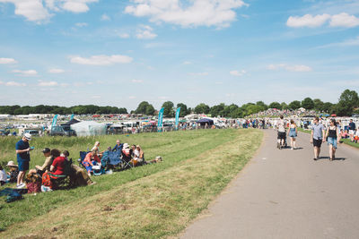 People enjoying at riverbank against sky