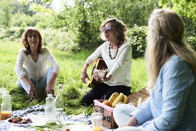 Group of women with guitar having fun at a picnic in park