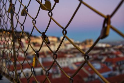 Close-up of padlocks on chainlink fence against sky