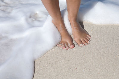 Low section of child standing on beach