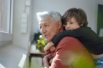 Contemplative senior man with grandson at home