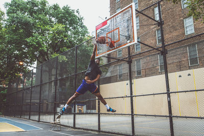 Young man scoring goal at basketball court