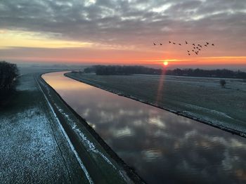 Scenic view of river against sky during sunset