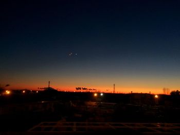 Illuminated city against sky at sunset