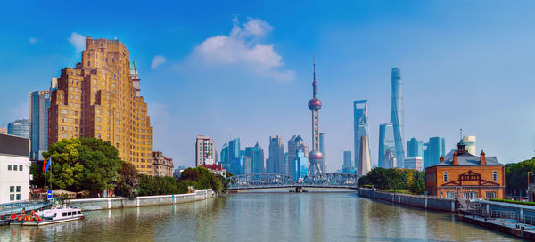 View of buildings by river in city against sky