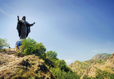 Man with arms raised against sky