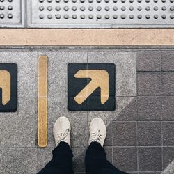 Low section of person standing on road sign