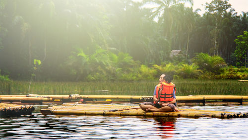 Man sitting in lake against trees