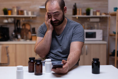 Midsection of man using mobile phone while sitting at table