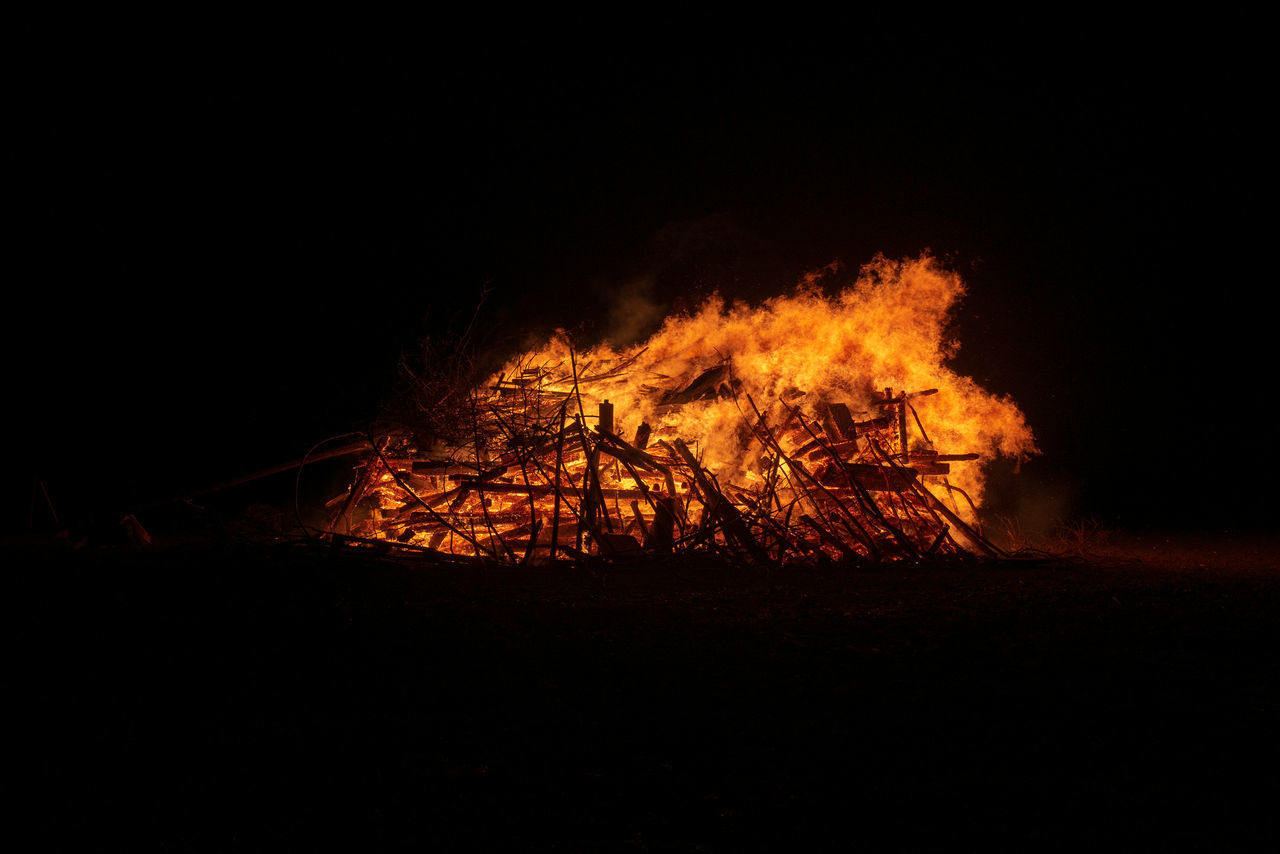 BONFIRE ON WOODEN STRUCTURE IN FIELD