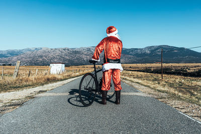 Rear view of man riding motorcycle on road against sky