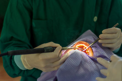 Midsection of male dentist operating patient in hospital