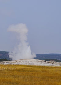 Steam emitting from volcanic landscape against clear sky