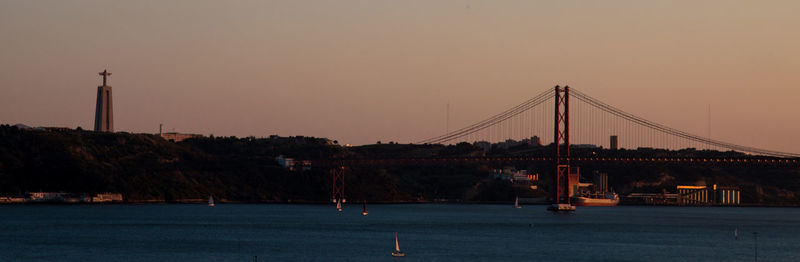 View of suspension bridge in city at sunset