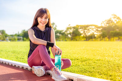 Portrait of smiling young woman sitting on field