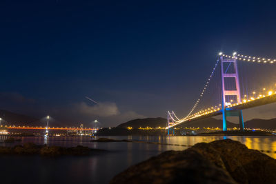 Illuminated bridge over river at night