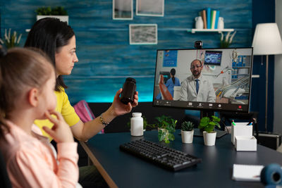 Mother and daughter consulting doctor through video call at home