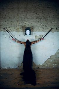 Woman with arms outstretched standing against wall