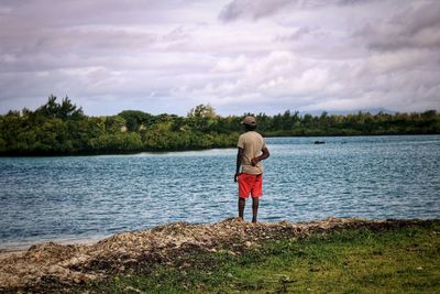 Rear view of man standing in lake against sky