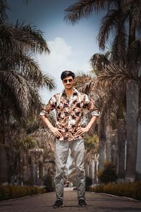 Portrait of man standing by palm tree