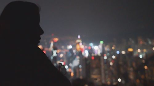 Silhouette woman against illuminated city at night