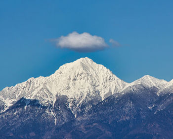 Snowcapped mountains against sky with a single cloud at the top of the peak